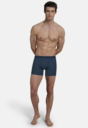 Navy blue boxer briefs with a geometric pattern, cotton material, fitted design, and a logoed waistband. Smooth texture and mid-thigh length.