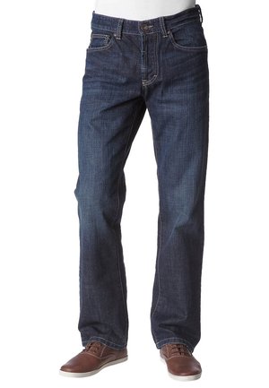 Męskie ciemnoniebieskie jeansy o prostych nogawkach w zestawie z brązowymi skórzanymi butami casual na białym tle.