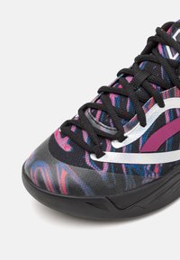 Gros plan d'une chaussure de sport noire avec un motif abstrait multicolore, lacets noirs, accents de design blancs et violets, et une semelle noire épaisse.