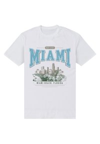 Hvid bomulds T-shirt med teksten "Next Stop Miami" i blå og grøn, samt grafik af Miami skyline og palmer.