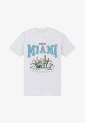 T-shirt en coton blanc avec l'inscription "Prochain Arrêt Miami" en texte bleu et vert, accompagné de graphiques de la skyline de Miami et de palmiers.