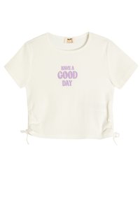 Camiseta de algodón blanca de manga corta con ribete y el texto "HAVE A GOOD DAY" impreso en lavanda. Presenta la opción de lazos ajustables en los laterales para personalizar el ajuste.