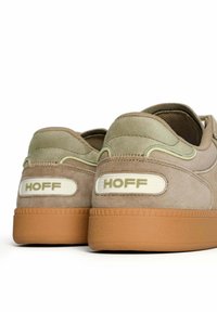 Sneaker in camoscio marrone con dettagli verdi, suola in gomma texturizzata e logo "HOFF" in rilievo sul tallone. Design con retro arrotondato e colletto imbottito.