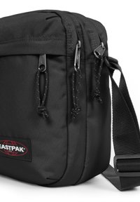 Borsa in tessuto nera con due scomparti con zip, tracolla regolabile e logo Eastpak. Presenta una superficie durevole e testurizzata.