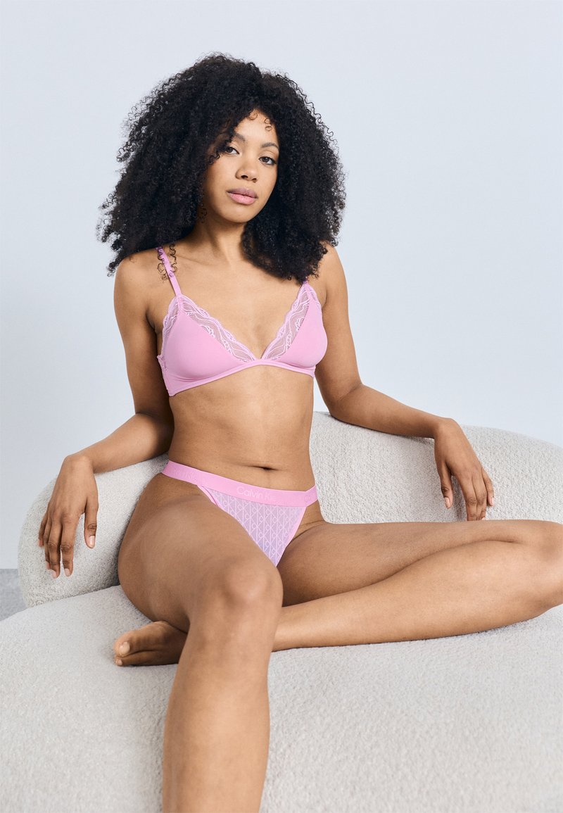 Ροζ σουτιέν με δαντέλα και ρυθμιζόμενους ιμάντες, συνδυασμένο με ροζ σλιπ με γεωμετρικό σχέδιο. Ομαλή υφή, casual σχεδιασμός.