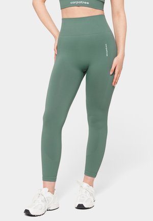 Hochtaillierte, olivgrüne Leggings aus stretchigem Stoff mit gerippten Details, versehen mit einem Logo auf der linken Seite und einer glatten Textur.