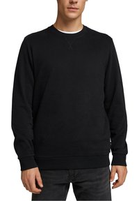 Sudadera negra hecha de tela suave, con cuello redondo, mangas largas y puños y dobladillo acanalados. Diseño minimalista sin logotipos visibles.