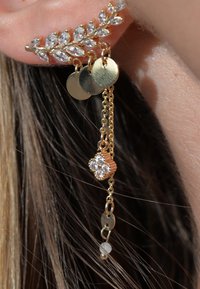 Boucles d'oreilles en forme de feuille d'or avec des rhinestones transparents, des chaînes pendantes et des accentuations métalliques circulaires. Comprend un pendentif floral avec des détails en cristal supplémentaires.