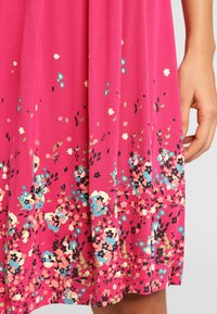 Pink floral dress featuring a vibrant print with blue, black, and white flowers, made from a soft, lightweight fabric, with a flared shape.