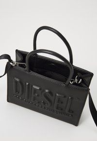 Borsa a tracolla in pelle nera con logo "DIESEL" in rilievo, design strutturato, doppi manici, tracolla rimovibile e tasca interna. Texture liscia.