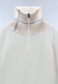 Crème kleurige gebreide trui met een hoge kraag, voorzien van een halve rits en subtiele gestreepte accenten in beige en lichtgrijs. Textuurstof.