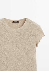 Haut en maille beige à manches courtes avec encolure ronde et détail subtil de volant sur les bords des manches.