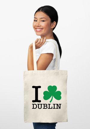 Torba na zakupy z płótna z napisem "Kocham DUBLIN". Zawiera czarny tekst z zielonym koniczynką. Jasny beżowy kolor, prosty design, dwa paski na ramię.