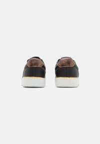 Black leather sneakers with brown textured accents, a white rubber sole, and gold detailing at the heel. Rear view focused on construction.