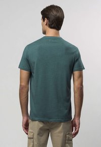 Grön bomulls-t-shirt med korta ärmar och rund hals, med en mjuk textur och en enkel, ren design. Bakre vy.