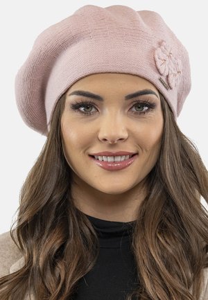 Beret rose en tricot avec un motif texturé et un accent floral. Le chapeau a une forme douce et arrondie ainsi qu'une étiquette en métal décorative.