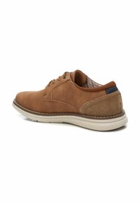 Zapato de cuero marrón con cordones, con una superficie lisa, suela beige contrastante y un talón trasero texturizado. El interior presenta un patrón a rayas.