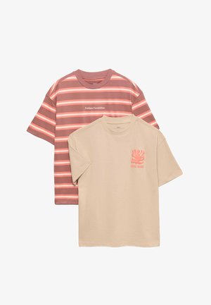 To kortærmede t-shirts, den ene beige med koralfarvet grafik og tekst, den anden stribet i nuancer af rød og pink med teksten "Endless Possibilities".