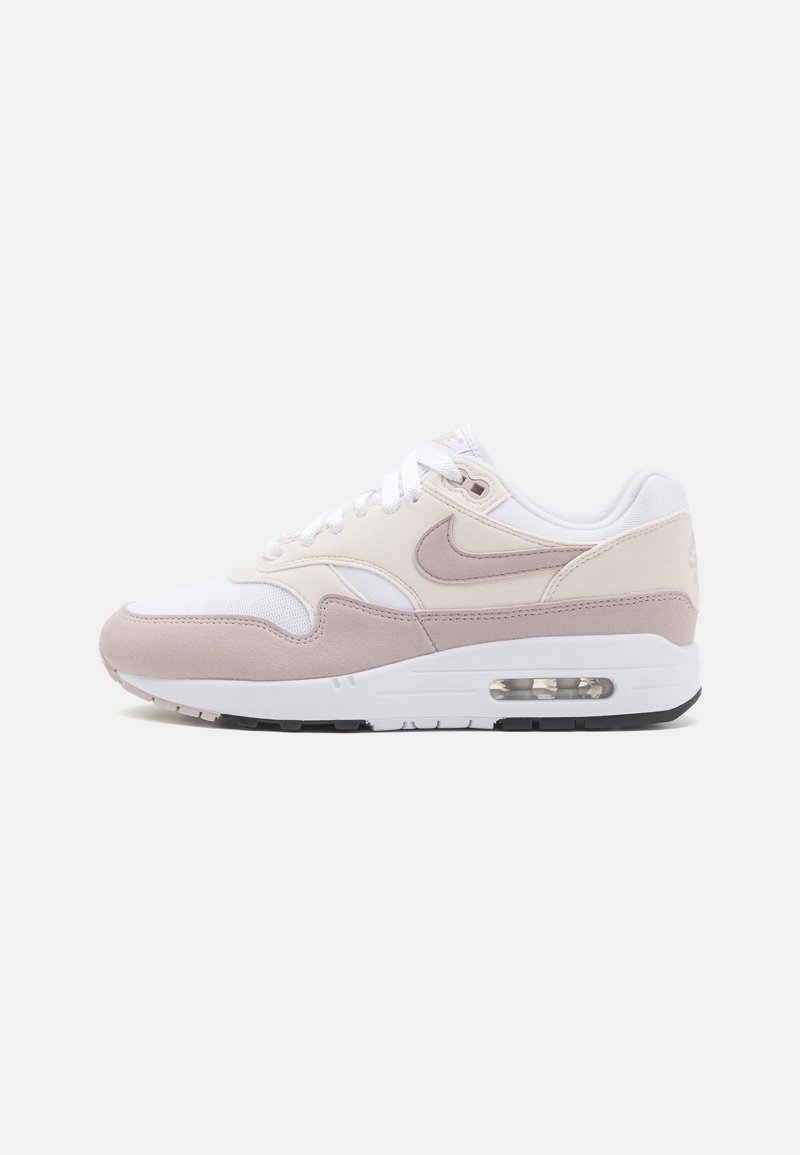 Scarpa da ginnastica Nike Air Max 1 bianca con accenti rosa pallido. Presenta un mix di materiali tra cui suede e mesh, con un'unità air visibile.