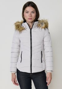 Párnázott fehér dzseki fekete cipzárral, levehet�ő műszőrme kapucnival, cipzáras oldalzsebekkel és átlós varrási részletekkel.