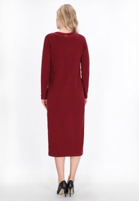 Langes burgunderrotes Kleid aus weichem Stoff, mit langen Ärmeln und rundem Halsausschnitt, gerader Passform und leicht abgerundetem Saum.
