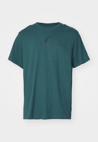 Teal bomullströja med korta ärmar och rundad hals, med en svart Jumpman-logotyp centrerad på bröstet.