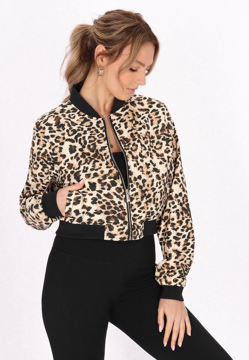 Giacca bomber tagliata in tessuto leopardato con polsini e cintura in rilievo neri. Chiusura frontale con zip e tasche laterali. Leggings neri.