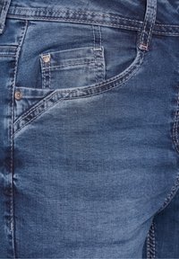 Jeans i denim med en medelblå tvätt, som har en framficka, subtila sömnadsdetaljer och en slät struktur med lätt urtvättning.