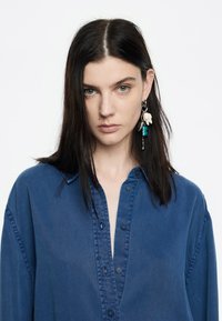 Niebieska koszula zapinana na guziki, wykonana z jednolitego materiału, z kołnierzykiem i slim fit. Wyróżniają się ciemnymi guzikami oraz teksturowaną powierzchnią.