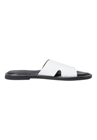 Mule avec une tige en cuir blanc, bout ouvert et design découpé. Semelle plate noire avec un détail de couture contrastant.
