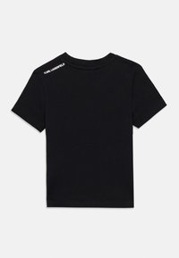 Μαύρο βαμβακερό μπλουζάκι με κοντά μανίκια, στρογγυλή λαιμόκοψη και λεία υφή. Φέρει λευκό λογότυπο "KARL LAGERFELD" στον πίσω ώμο.