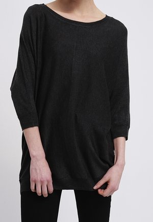 Haut noir ample avec un décolleté large et des manches trois-quarts. Texture douce avec une silhouette légèrement drapée.