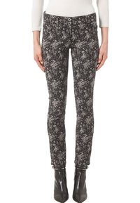 Czarne obcisłe dżinsy z białym kwiatowym wzorem, z zapięciem na guzik i szlufkami na pasek, wykonane z miękkiego materiału, zestawione z czarnymi, szpiczastymi botkami za kostkę.