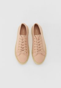 Light pink canvas sneakers with gold eyelets and beige jute soles. Rounded toe design and flat laces, featuring a simple and clean aesthetic.