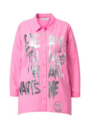 Chemise rose à manches longues, ornée d'un grand texte argenté et d'un motif de smiley avec des cœurs à la place des yeux. Tissu lisse et coupe décontractée.