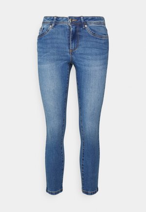Niebieskie obcisłe jeansy z denimu z frontowym guzikiem, zamkiem błyskawicznym i pięciokieszeniowym designem na białym tle.
