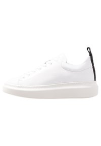 Białe skórzane trampki z okrągłym czubkiem, tonowane sznurowadła, podwyższona biała podeszwa oraz czarny akcent na pięcie. Gładka faktura na całej powierzchni.