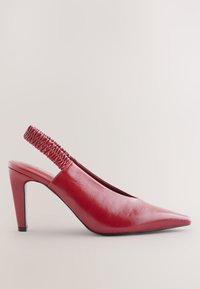 Escarpin slingback en cuir rouge avec un bout pointu, une bride élastique texturée au talon et un talon stiletto de hauteur moyenne. Finition lisse et design élégant.
