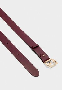 Cintura in pelle bordeaux con una texture liscia, dotata di una fibbia in metallo dorato con un design distintivo e diversi fori di regolazione.
