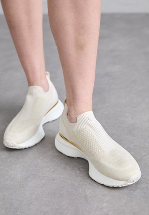 Svijetlosmeđi sportski tenisice s rebrastim pletenim gornjim dijelom, teksturiranom obradom i bijelom potplatom s zlatnim naglaskom. Dizajn za jednostavno obuvanje.