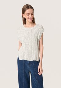 Top corto a maniche corte di colore grigio chiaro, realizzato in maglia con una texture a coste e una vestibilità comoda. Abbinato a jeans a gamba larga di colore blu scuro. Nessun motivo o dettaglio visibile.