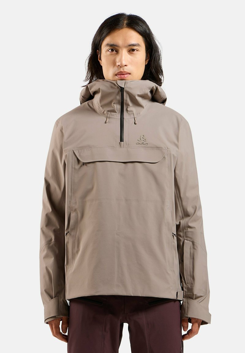 Beige wasserfeste Jacke mit hohem Kragen, Reißverschluss und Fronttasche; verfügt über eine verstellbare Kapuze und verstellbare Bündchen; glatte Textur.