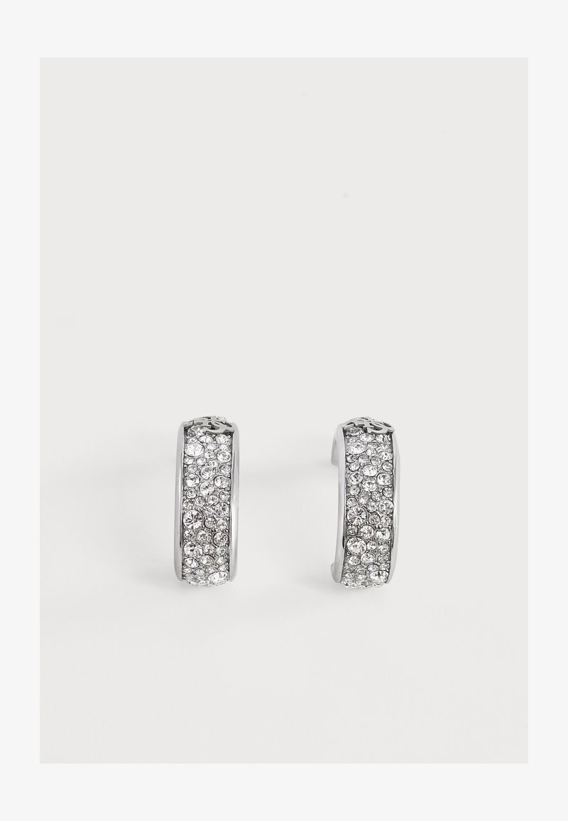 Paire de boucles d'oreilles créoles en argent incrustées de petits strass transparents sur un fond blanc uni.