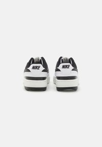 Black and white Nike sneakers, featuring a smooth leather outer, mesh accents, padded collar, and a rubber sole with a textured grip.