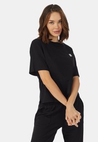 Czarny t-shirt z krótkim rękawem, okrągły dekolt, luźny krój, z małym białym logo na piersi, wykonany z miękkiej bawełny.