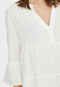 Witte blouse met een V-hals, lange mouwen en gerimpelde manchetten, met gemengd textiel en een gelaagd ontwerp.