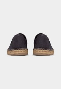Paire d'espadrilles noires en daim avec semelles intermédiaires en jute tressé et semelles extérieures en caoutchouc plat, vues de dos sur fond blanc.