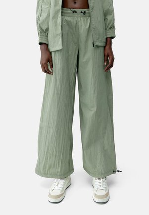 Licht olijfgroen wijde broek met een gestructureerde, lichte stof. Heeft een elastische tailleband met koordjes en zijzakken.