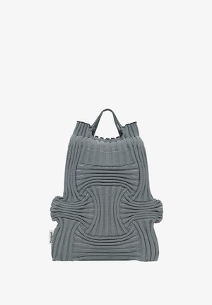 Sac fourre-tout gris avec des lignes texturées et ondulées, doté de deux courtes poignées. Fabriqué à partir d'un matériau flexible, avec un design distinct en forme de croix.