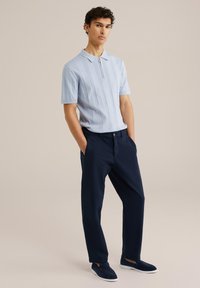 Polo shirt ribbed azzurro chiaro con maniche corte e mezza zip, abbinato a pantaloni chinos blu navy e scarpe slip-on blu navy. Design e texture semplici.